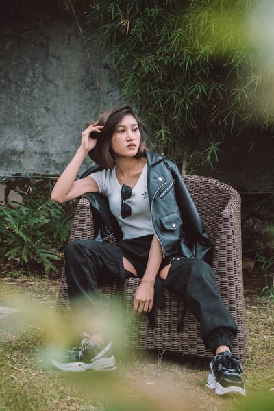 穿着黑白校服坐在黑色柳条椅上的妇女